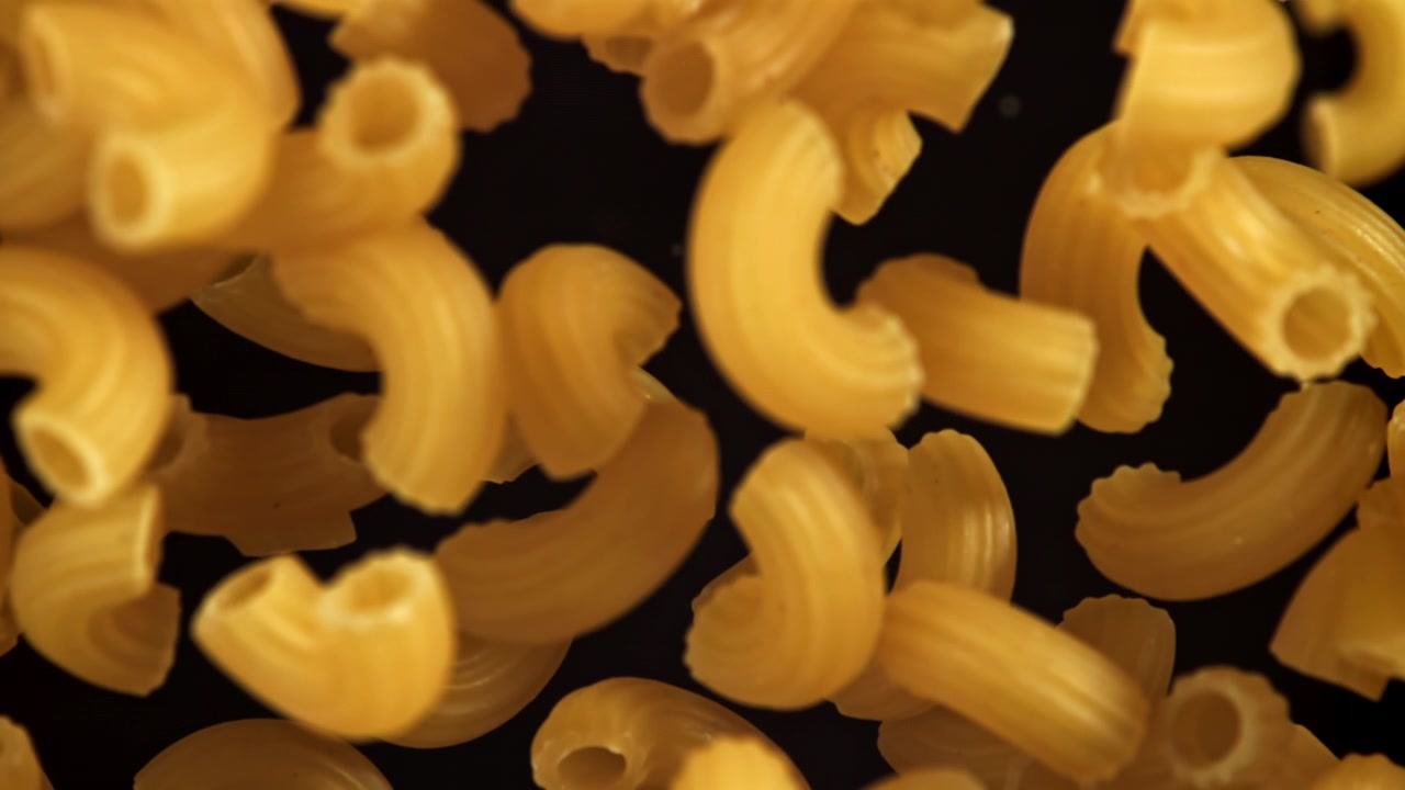 Primo piano di maccheroni secchi che cadono al rallentatore.