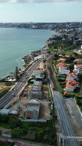 Vertical aerial following a train on the coastline of Estoril, in sunny Portugal
