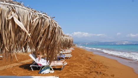 tourists relaxing on the red sand shore of megas lakkos beach at daytime, cephalonia island, greece, europe - static shot