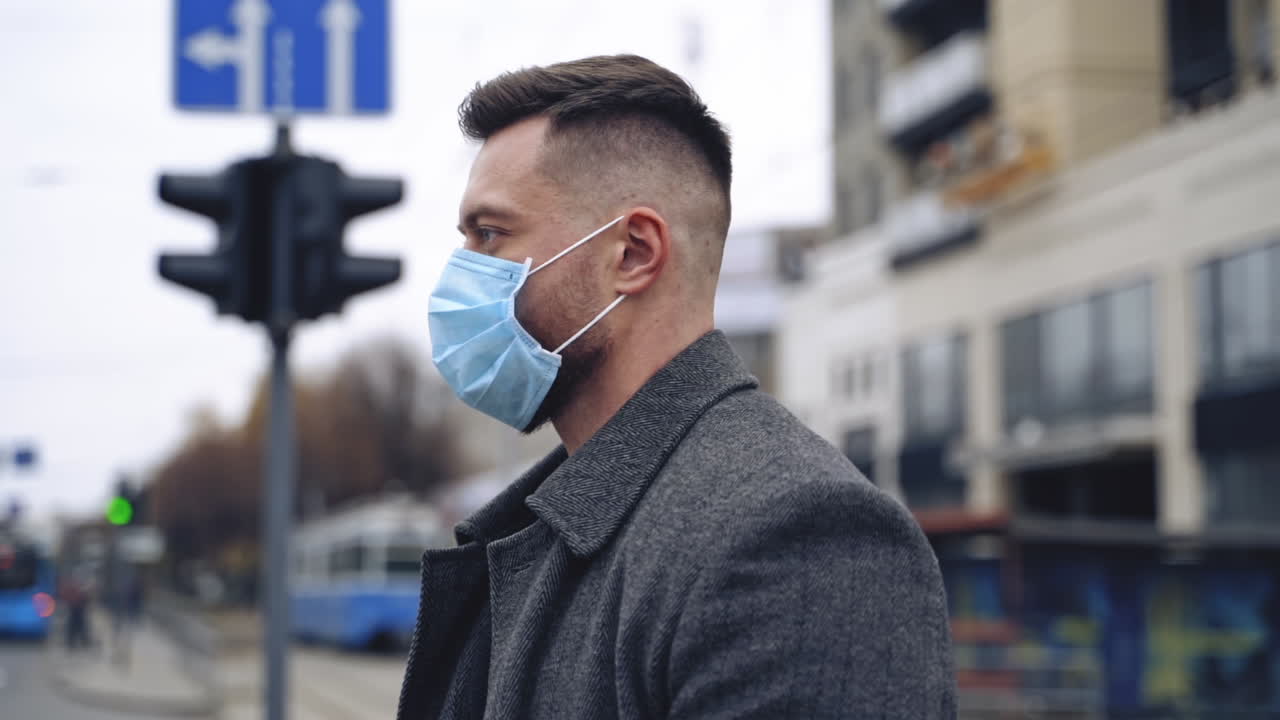 COVID-19. Man in city street wearing face protective mask against spreading coronavirus. Portrait of a male in coat and suit.