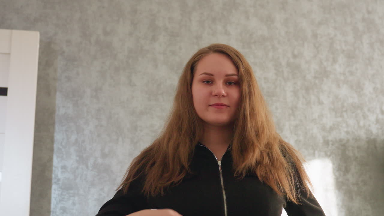 Ritratto di modella con trucco impeccabile che ruota con grazia, agitando i lunghi capelli castani, in posa dinamica in una stanza luminosa, mettendo in mostra eleganza, movimento e bellezza naturale
