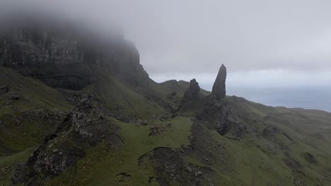 4k aerial drone footage zooming in from fog and mist to clear view of old man of storr isle of skye scotland uk rocks mountains