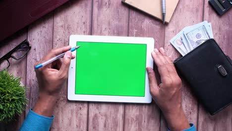 person working on a tablet with green screen, office workspace