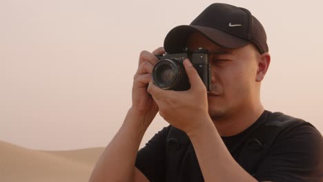 professional photographer in the desert taking pictures in old soviet era camera zenit