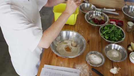 caucasian female chef adding an egg into a bowl