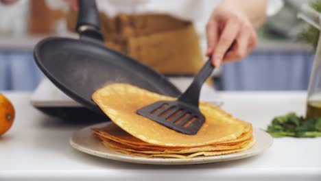 cocinero anónimo poniendo un panqueque encima de otro panqueque