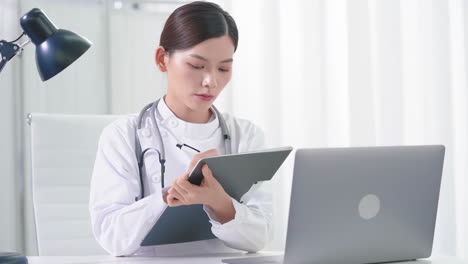 Portrait-female-specialist-doctor-with-stethoscope-writes-medical-prescription-for-patient-at-appointment-on-a-tablet-computer-table-inside-a-hospital-ward-clinic