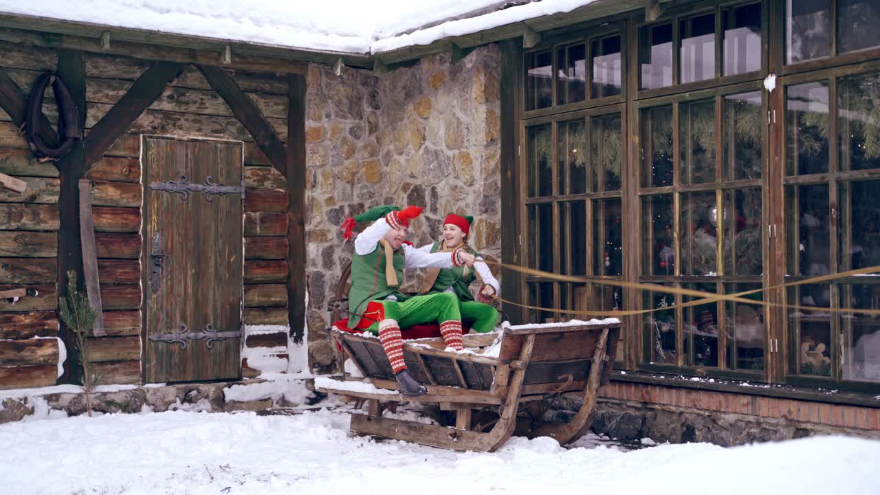 Noel elfleri ahşap kızaklara biniyor. Yeni yıl geliyor. Noel arifesi. Erkek ve kız çocuk Noel kıyafetleri giyiyor. Eğleniyorlar.