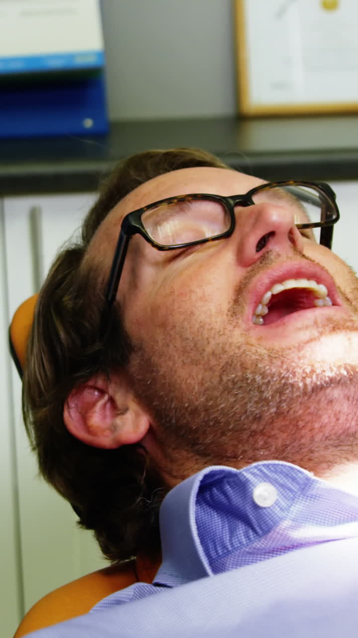 asistente de dentista sonriente ajustando la luz dental sobre la boca de los pacientes