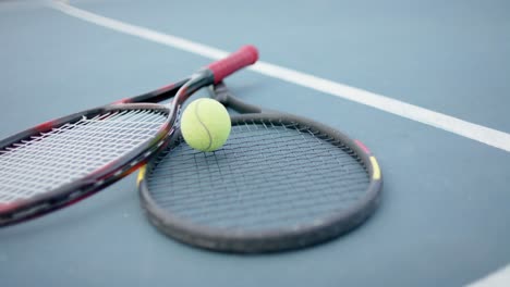 Close-up-of-tennis-rackets-and-ball-on-outdoor-tennis-court,-slow-motion