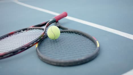 close up of tennis rackets and ball on outdoor tennis court, slow motion