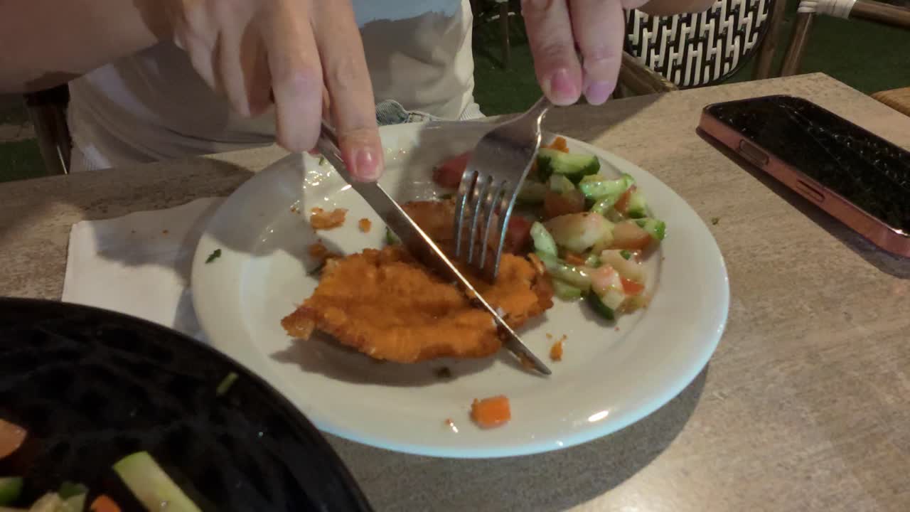 Close-up of Hands Cutting a Fried Schnitzel with a Knife