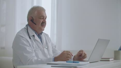 médico está consultando on-line sentado no escritório de uma clínica privada usando laptop para falar com o paciente tecnologia de telemedicina