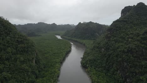 Aerial-rises:-Lone-boat-motors-on-misty-Malaysia-tropical-jungle-river