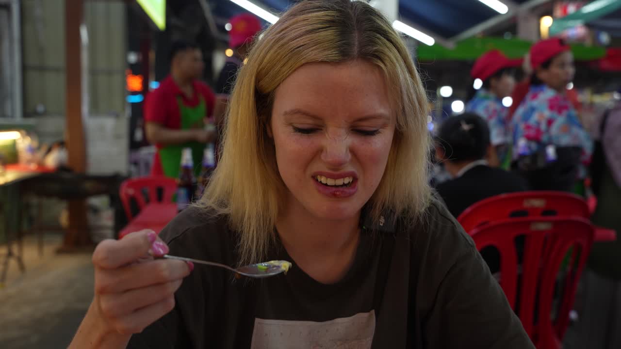 젊은 금발 여자 는 맛 이 나쁜 것 을 먹는 동안 얼굴 을 짓는다