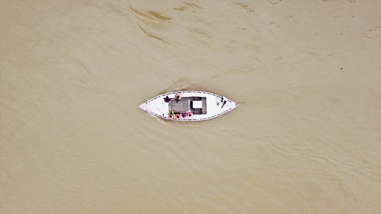 serenas imágenes aéreas de arriba hacia abajo de un pequeño barco deslizándose a lo largo del río ganges en la india