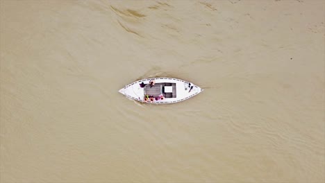 serenas imágenes aéreas de arriba hacia abajo de un pequeño barco deslizándose a lo largo del río ganges en la india