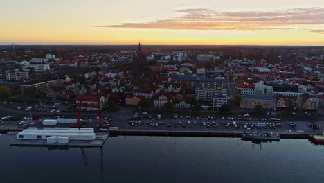 Toma-Aérea-Hacia-Atrás-De-La-Ciudad-De-Slottsholmen-Con-Iglesia,-Edificios-Antiguos-Y-Frente-Al-Mar-Al-Atardecer