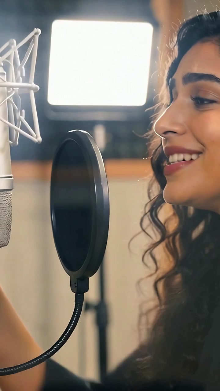 Video verticale: Vocalist che risponde a un segnale, cantando in un microfono in studio con filtro anti-pop, con spazio per il testo.