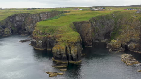 tiro de dron giratorio del refugio de ballenas que pasa por los acantilados rocosos de 250 pies con vistas al mar del norte en escocia