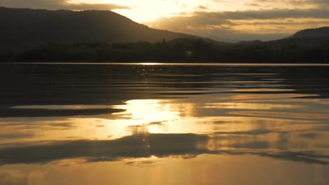 Hermosa-Puesta-De-Sol-Reflejada-En-El-Agua-Con-Montañas-En-El-Fondo