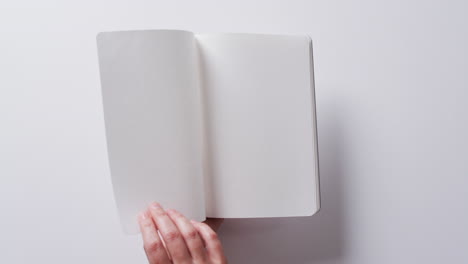 close up de la mano hojeando un libro con espacio de copia en un fondo blanco en cámara lenta