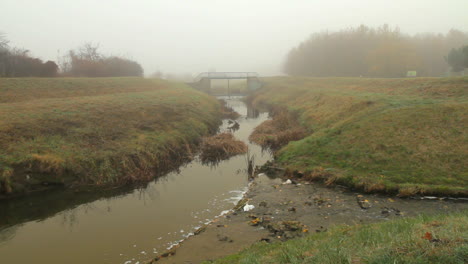 A-small-stream-runs-through-the-park-during-a-misty-foggy-morning