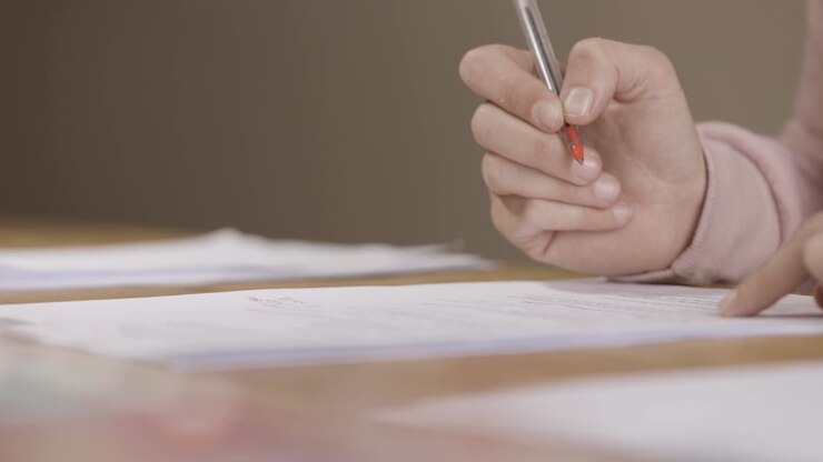Teacher marking paper with a red pen