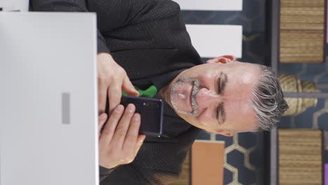 Vertical-video-of-Happy-businessman-using-phone-laughing.