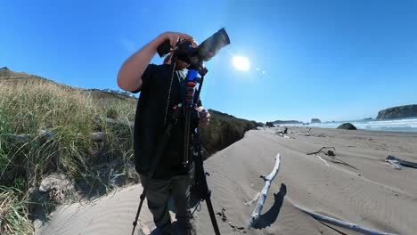 un fotógrafo en el día del cielo azul filmando en la playa de bandon