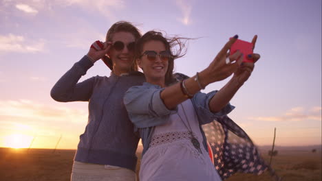 Schöne-Freundinnen-Machen-Selfies-Auf-Einem-Roadtrip-Bei-Sonnenuntergang-Mit-Einem-Oldtimer