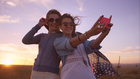 Hermosas-Amigas-Tomando-Selfies-En-Un-Viaje-Por-Carretera-Al-Atardecer-Con-Un-Coche-Antiguo