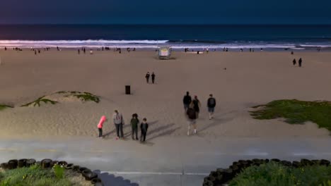 people walking at the strand of beach at night with wavy ocean