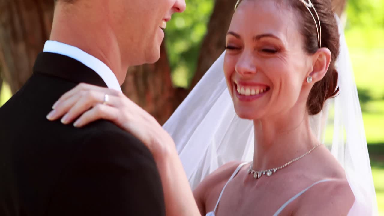 신혼 부부가 함께 춤을 추고 카메라에 미소 짓고 있습니다.