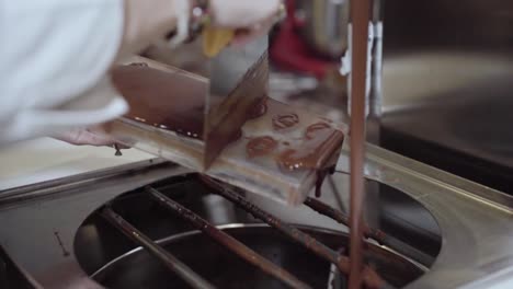 chocolatier scraping off excess liquid chocolate from mould top surface