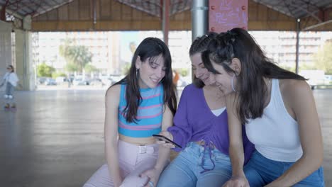 three young women looking at a smartphone