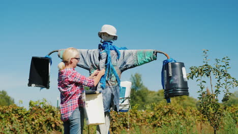 woman adjusting scarecrow