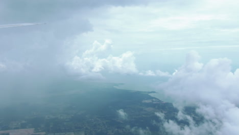 view from the airplane window - clouds and landscape under the wing of a plane flying from australia to singapore - aerial, pov