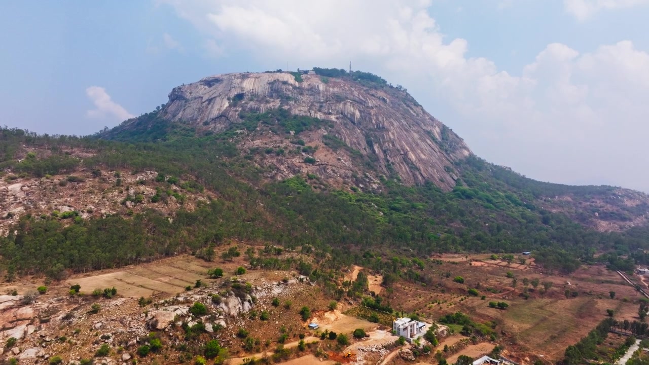 Dyrket mark med landområder, trær og Nandi Hills i Bangalore, Karnataka, India. Dagtid, kranbilde, dronebilde, 4K.