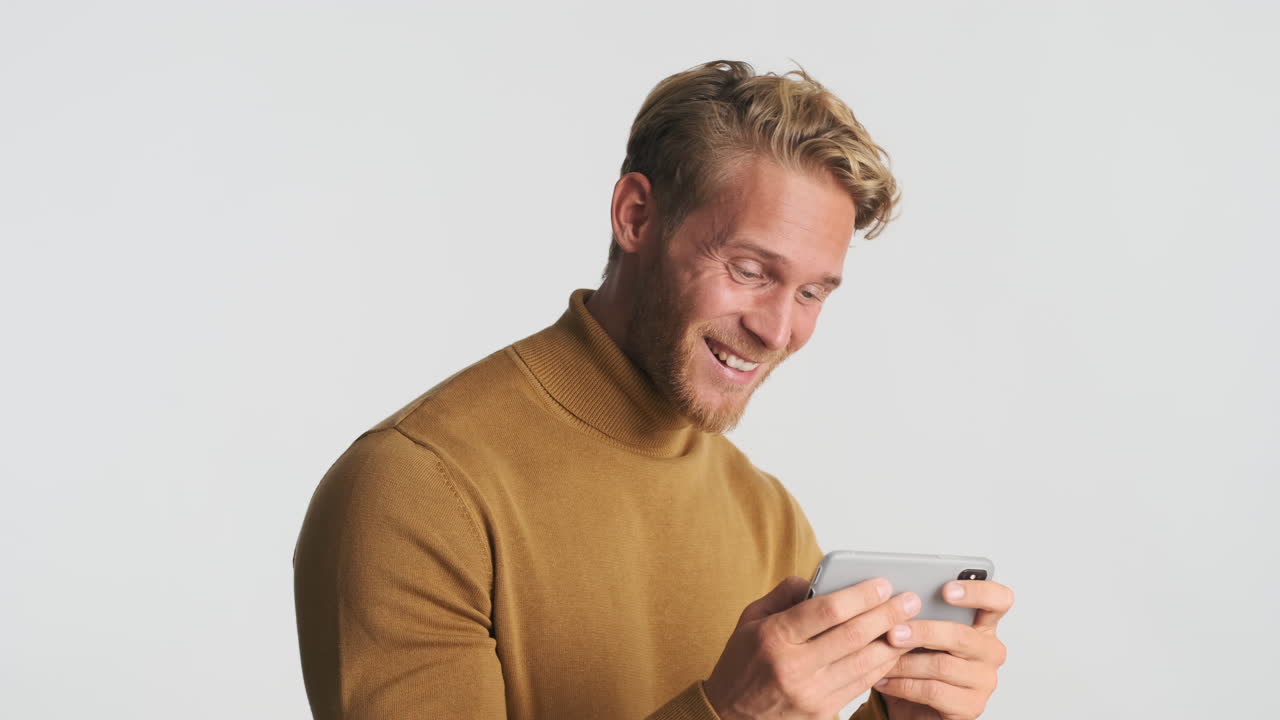 Cheerful man using smartphone for playing