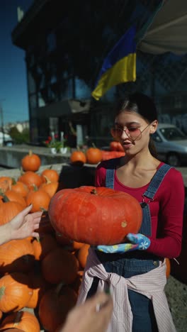 mujer seleccionando una calabaza grande en un mercado de otoño