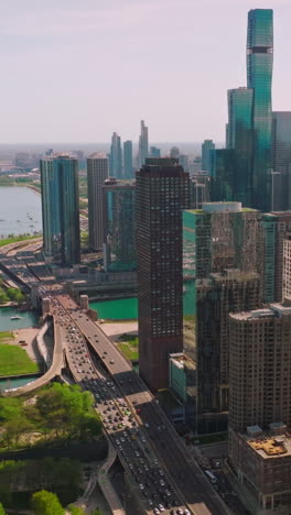 incredible skyscrapers neighboring turquoise waters of the lake michigan. drone footage of chicago buildings, green areas, multi-lane roads and scenic view of a lake. vertical video