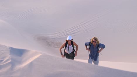 Paar-Mit-Rucksack-Klettert-Die-Sanddüne-Hinauf-4k