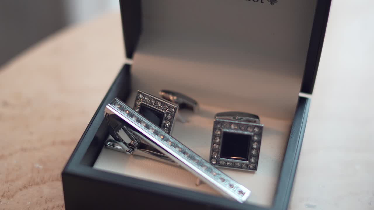 Cufflinks in their black box on a table, during the groom's preparation for his wedding day