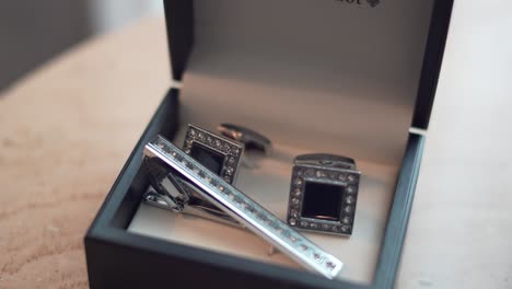 Cufflinks in their black box on a table, during the groom&#039;s preparation for his wedding day