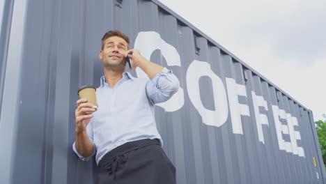 female owner of coffee shop or distribution business standing by shipping container