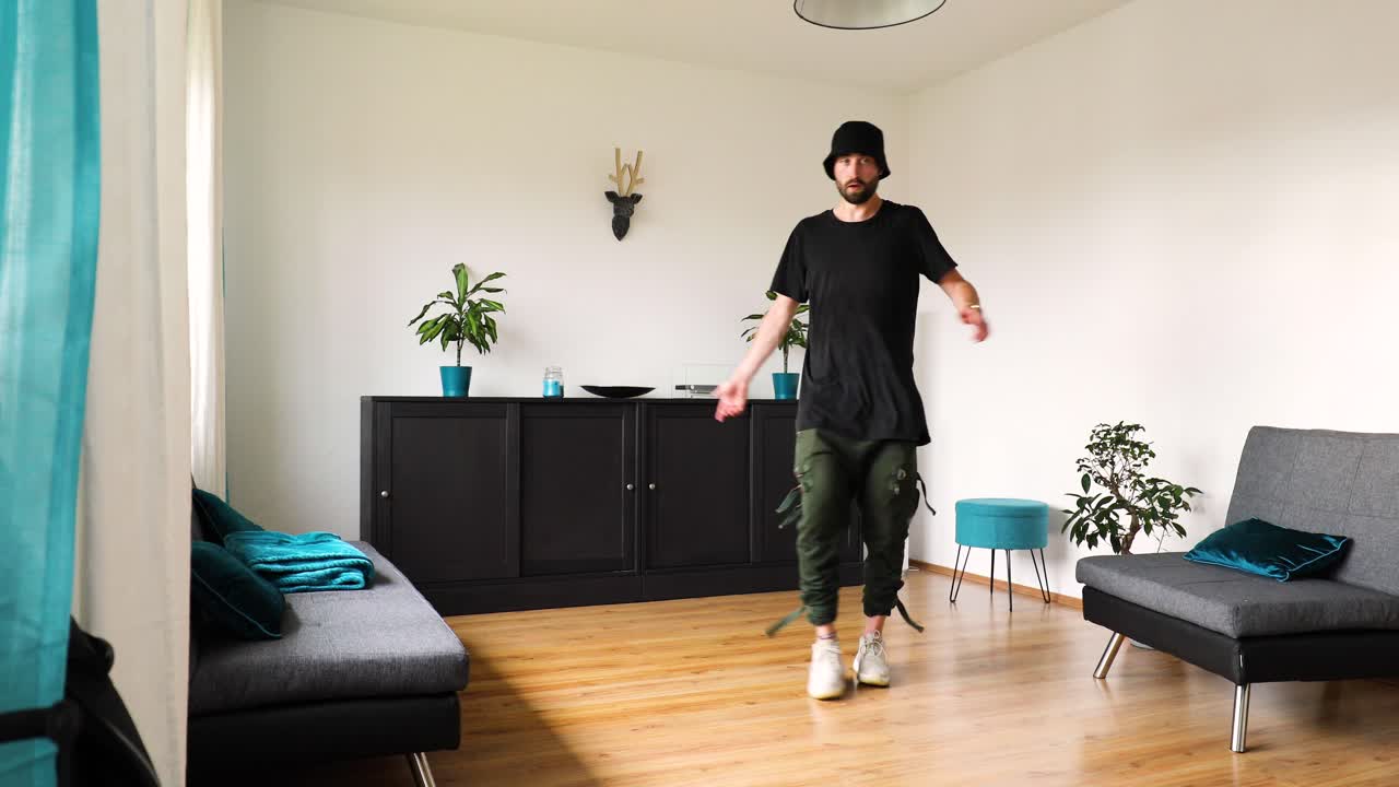 young man dances in the living room and trains his dance steps