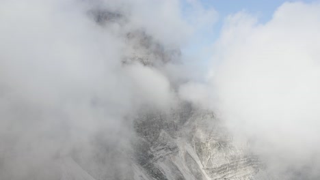 Flying-in-between-the-clouds,-big-mountain-peaking-behind-background,-Tre-Cime-National-Park,-Italy