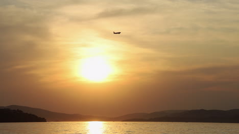 silhouette of an airplane over the tropical bay at sunset