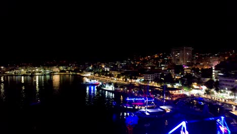 night harbor elegance: leisure tour ships gracefully anchored on saranda's coastal pier, illuminated by neon lights, creating a mesmerizing scene